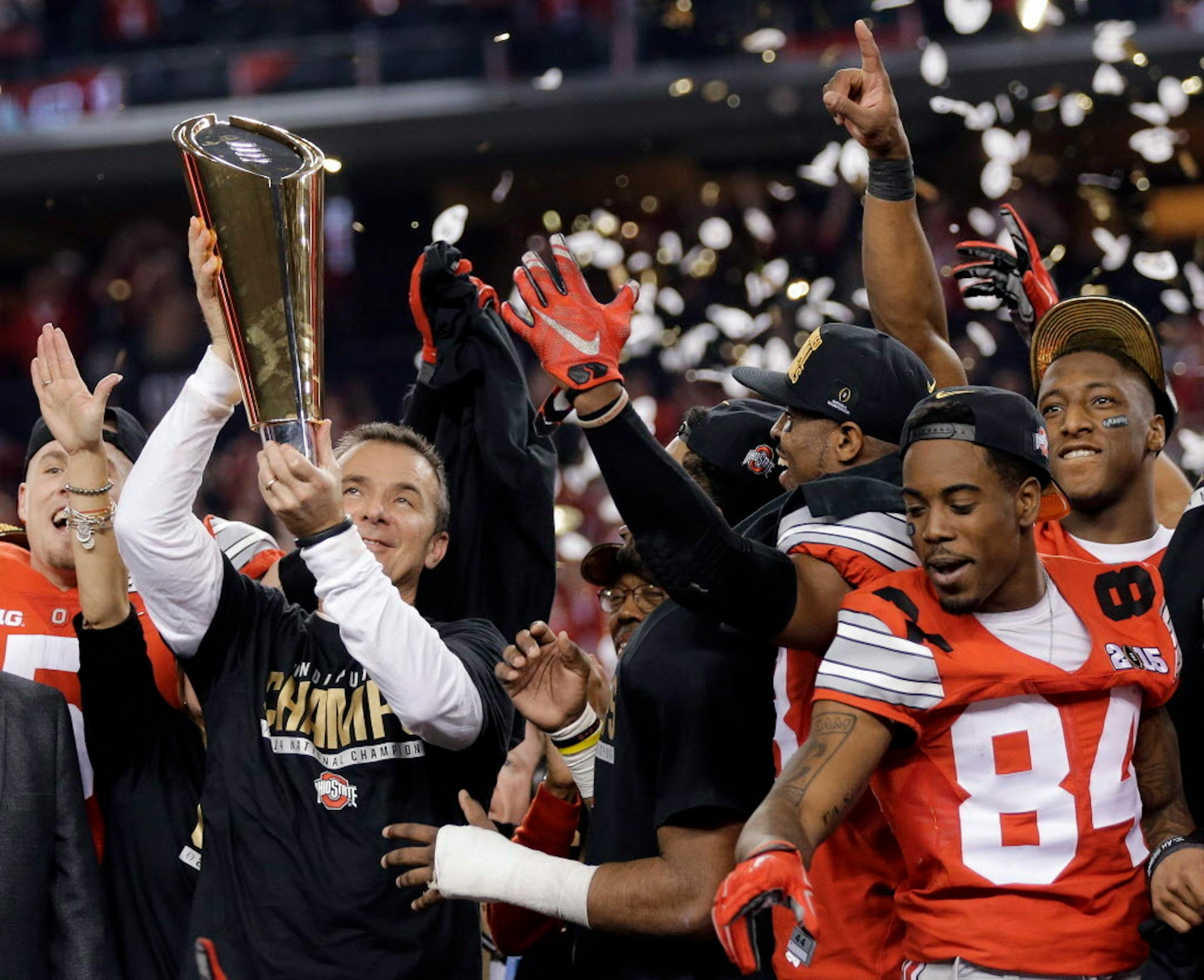 FILE - In this Jan. 12, 2015, file photo, Ohio State coach Urban Meyer holds the trophy and celebrates with his team after the NCAA college football playoff championship game against Oregon in Arlington, Texas.