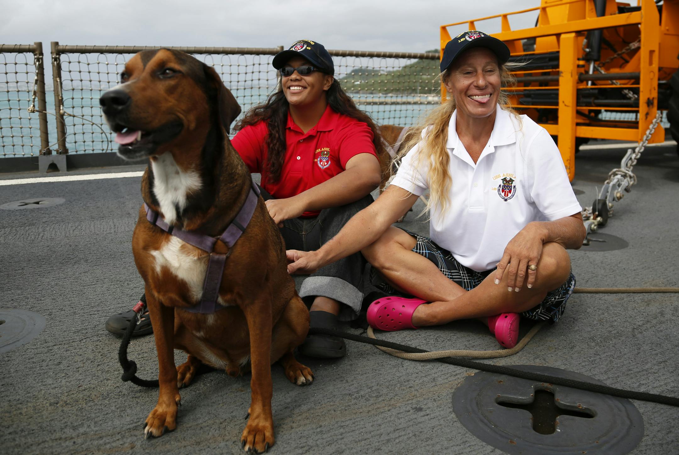 Jennifer Appel, right, and Tasha Fuiava sit with one of their dogs on the deck of the USS Ashland Monday, Oct. 30, 2017, at White Beach Naval Facility in Okinawa, Japan. The U.S. Navy ship arrived at the American Navy base, five days after it picked up the women and their two dogs from their storm-damaged sailboat, 900 miles southeast of Japan. (AP Photo/Koji Ueda)