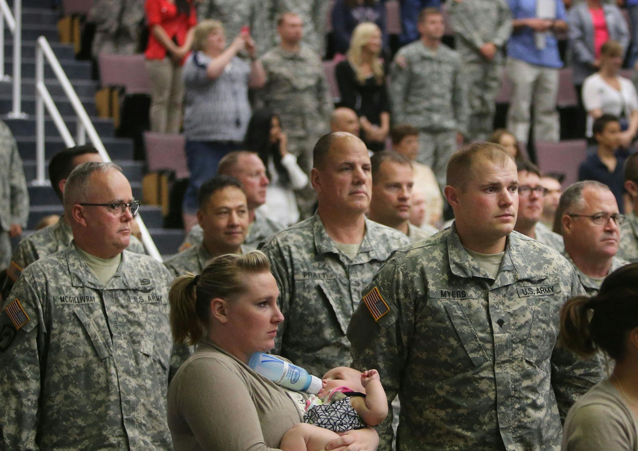 Spc. Kyle Myers, front right, stands for the National Anthem with his wife Caitlin and daughter Charlotte, 6 months.