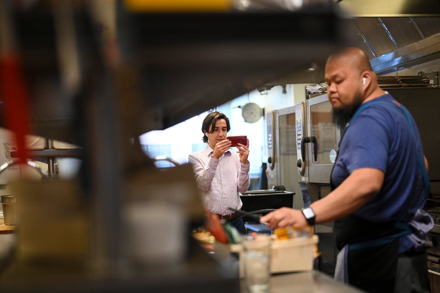 Kyle Kvamme, left, communications coordinator for Open Arms of Minnesota, operated one of two cameras for the live stream as chef Yia Vang taught viewers how to cook a fried ramen noodle dish.