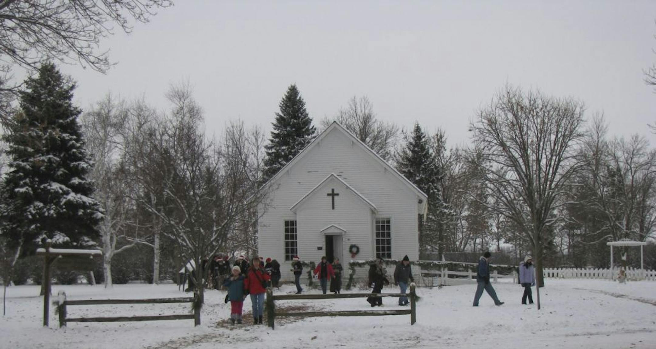 Visitors stroll from�the 1900s-era church after singing Christmas carols, one of many activities available during Dakota City's Christmas in the Village.�