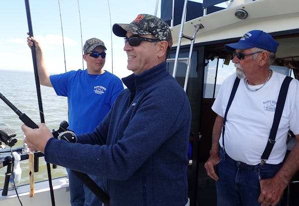 Scott Ward of Inver Grove Heights reeled in a lake trout under the watchful eye of charter boat captain Peter Dahl, right, and his 15-year-old first m