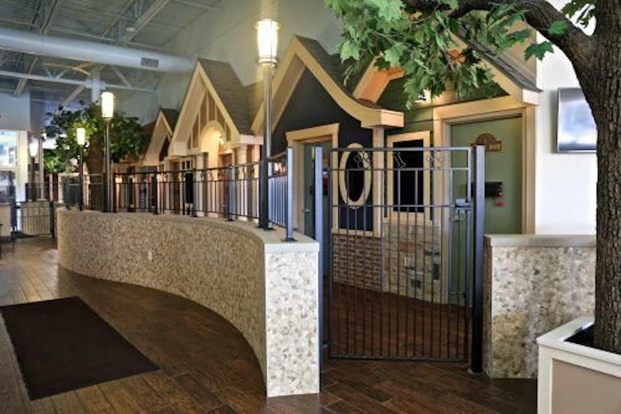 This August 2015 photo provided by Bigger Road Veterinary Center for Pet Health and Enrichment shows the exam rooms at the facility in Springboro, Ohio. To the right is one of the support beams that was turned into a tree. The exam rooms, designed to look like forest cottages, follows the path, with street lamps along the way.