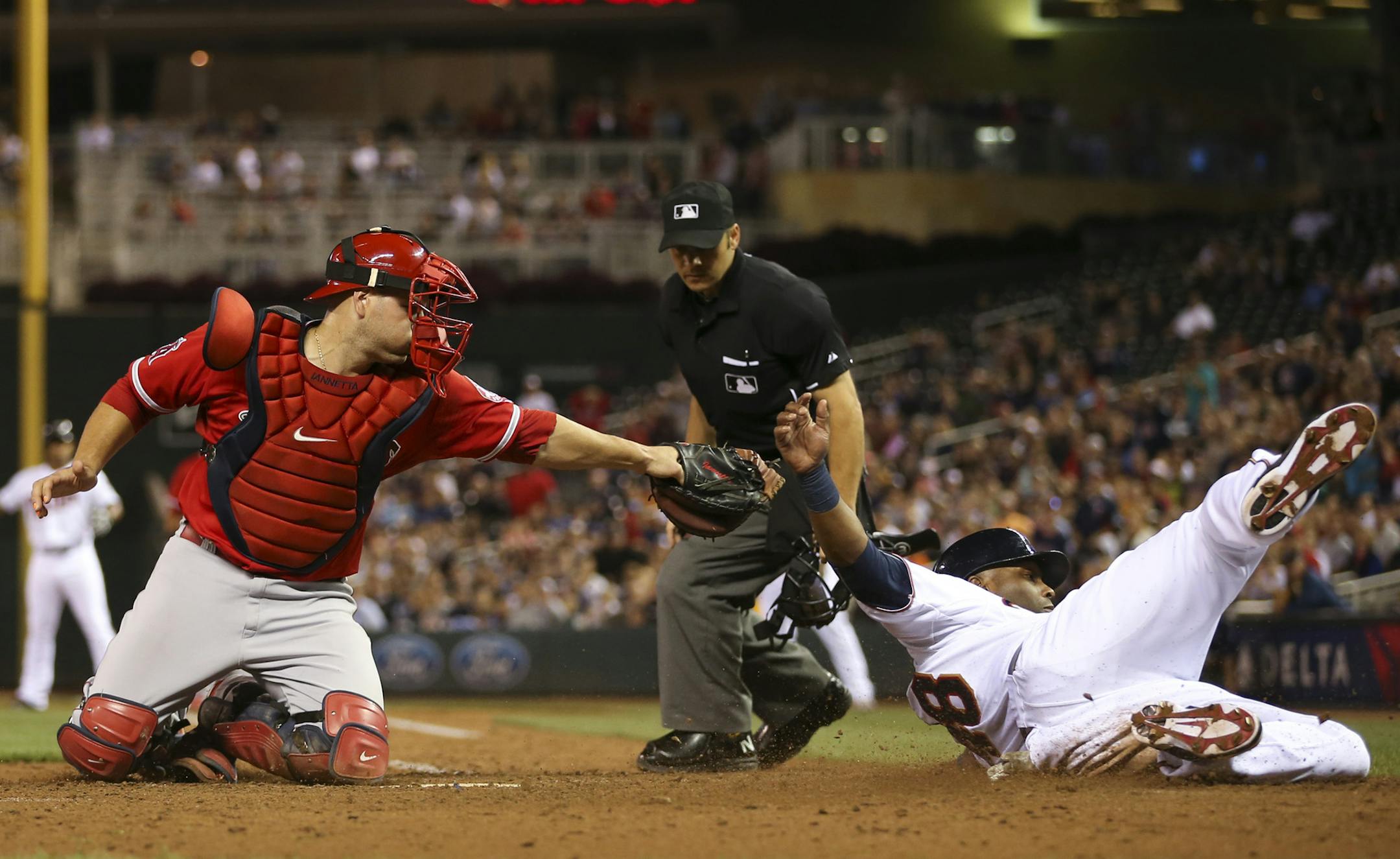 Twins right fielder Torii Hunter (48) slid under the tag of Los Angeles Angels catcher Chris Iannetta (17) to score on a single by Eduardo Escobar in the third inning Thursday night at Target Field.