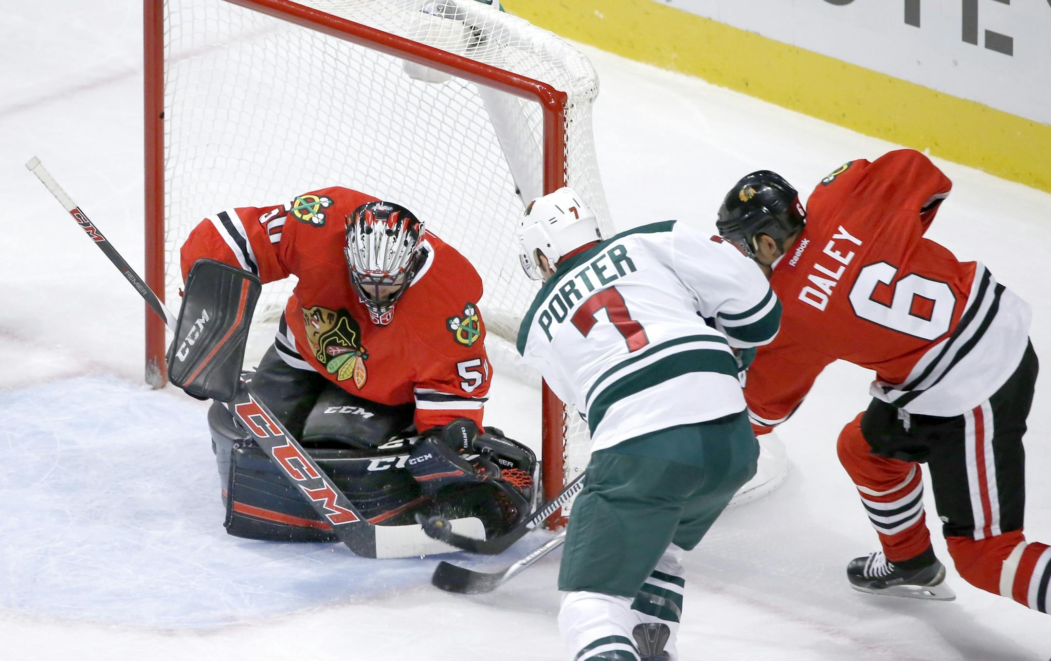 Chicago Blackhawks goalie Corey Crawford makes a save on a shot by Minnesota Wild left wing Chris Porter (7) as Trevor Daley also defends during the first period of an NHL hockey game Tuesday, Dec. 1, 2015, in Chicago. (AP Photo/Charles Rex Arbogast)