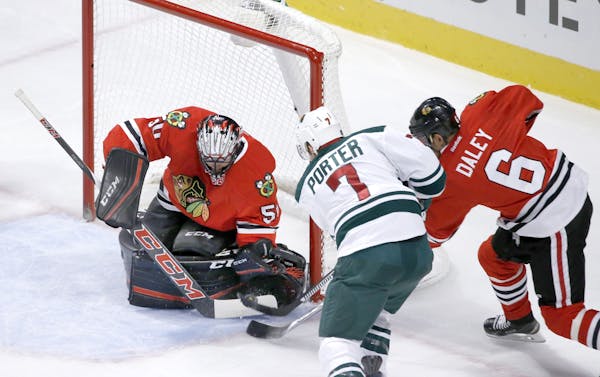 Chicago Blackhawks goalie Corey Crawford makes a save on a shot by Minnesota Wild left wing Chris Porter (7) as Trevor Daley also defends during the f