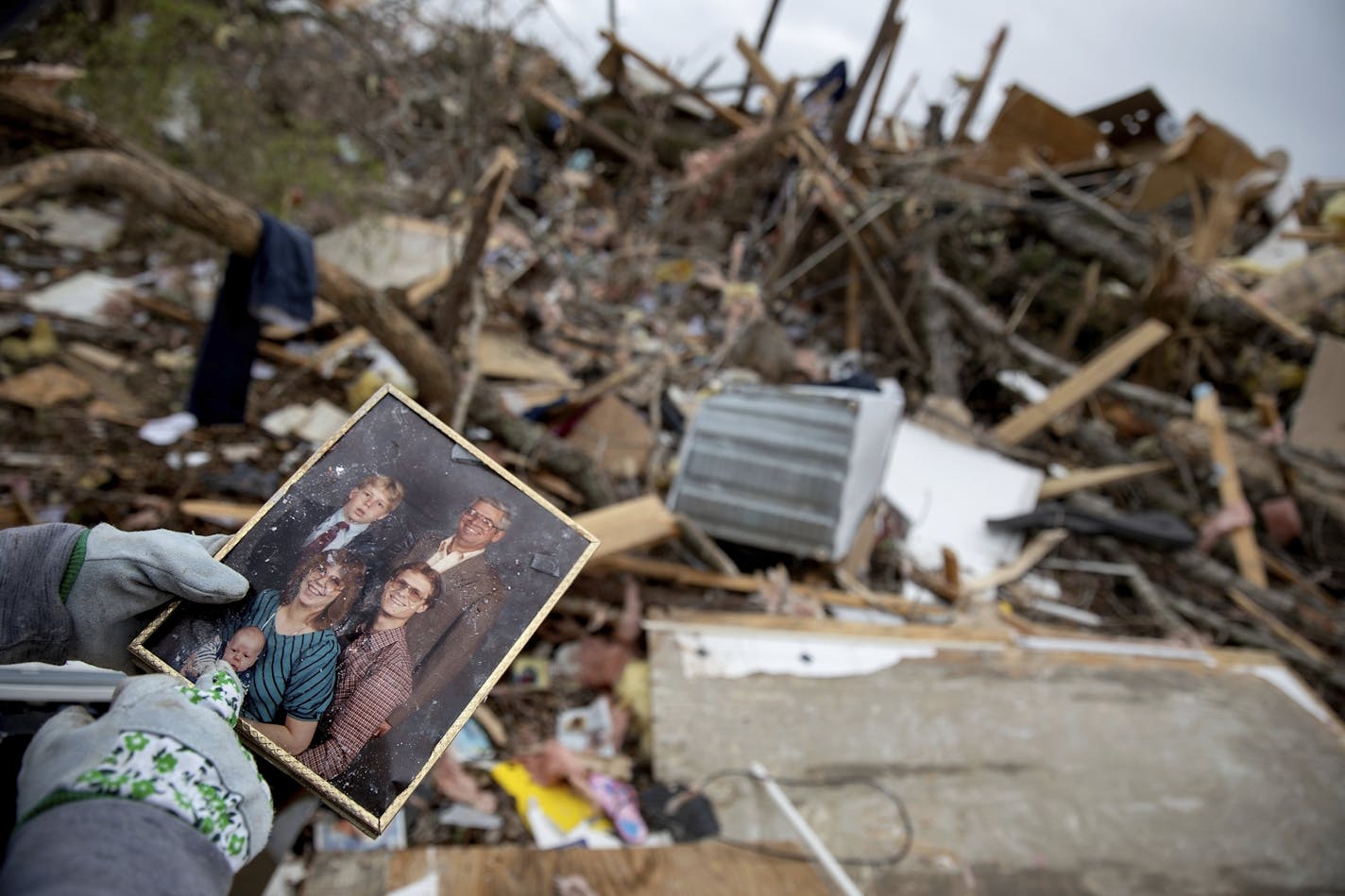 Danny Allen recovers a family photo while sifting through the debris of a friend's home destroyed by a tornado in Beauregard, Ala., Monday, March 4, 2019.