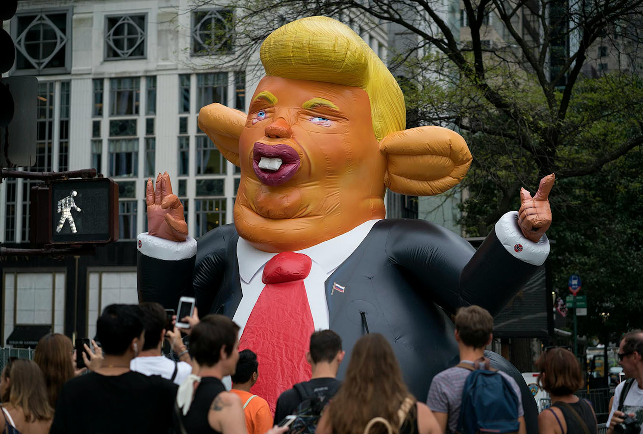 An inflatable caricature of President Donald Trump rises above pedestrians at W. 59th Street and 5th Ave., in New York Monday, Aug. 14, 2017, just three blocks north of Trump Tower.