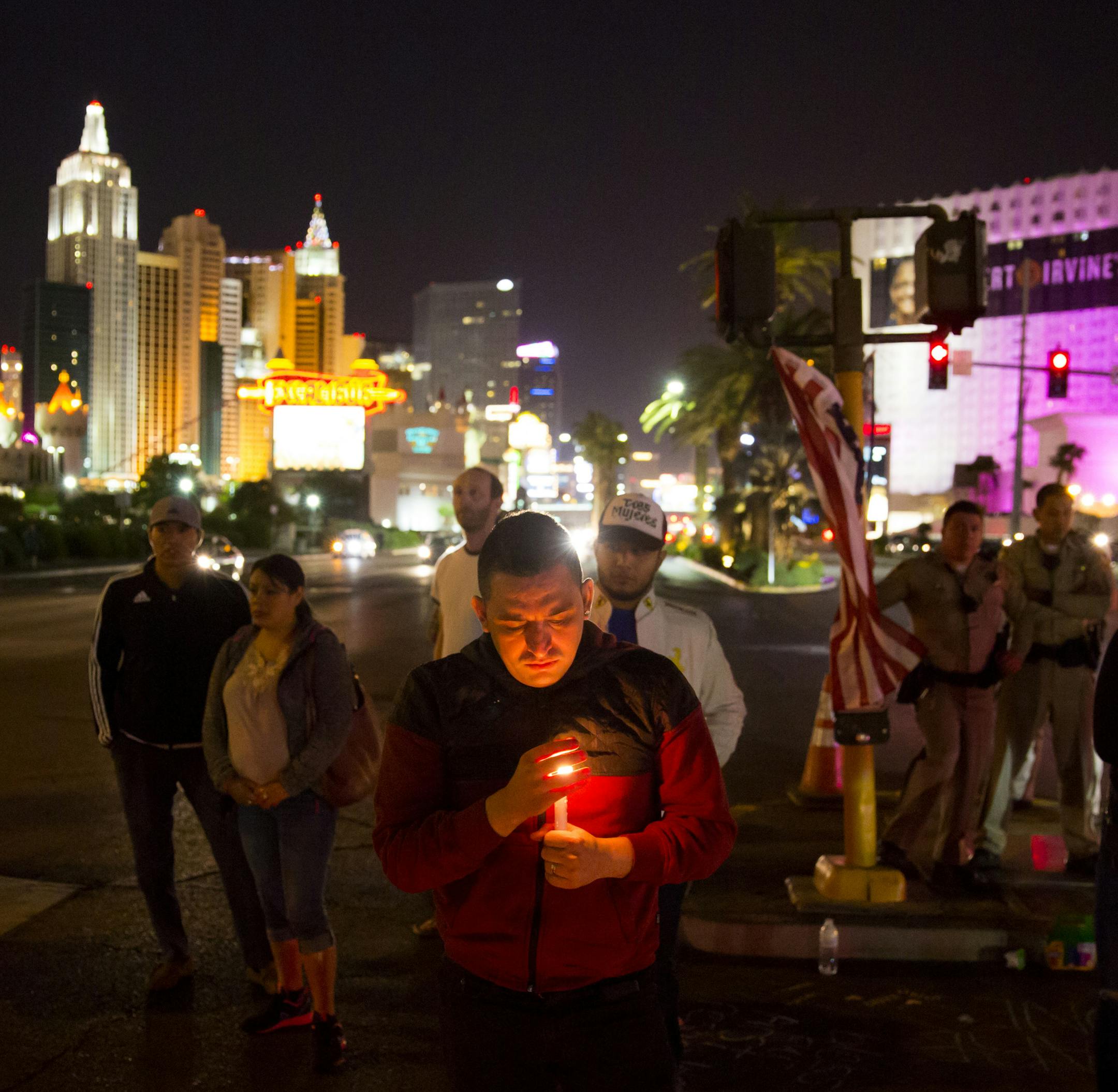 People gather at a makeshift memorial on the Las Vegas Strip in the early morning hours of Oct. 4, 2017. A lone gunman, identified as Stephen Paddock, fired down from a 32nd-floor suite at the Mandalay Bay Resort and Casino upon a crowded country music festival on Sunday night, killing at least 59 and injuring more than 500. (Eric Thayer/The New York Times)