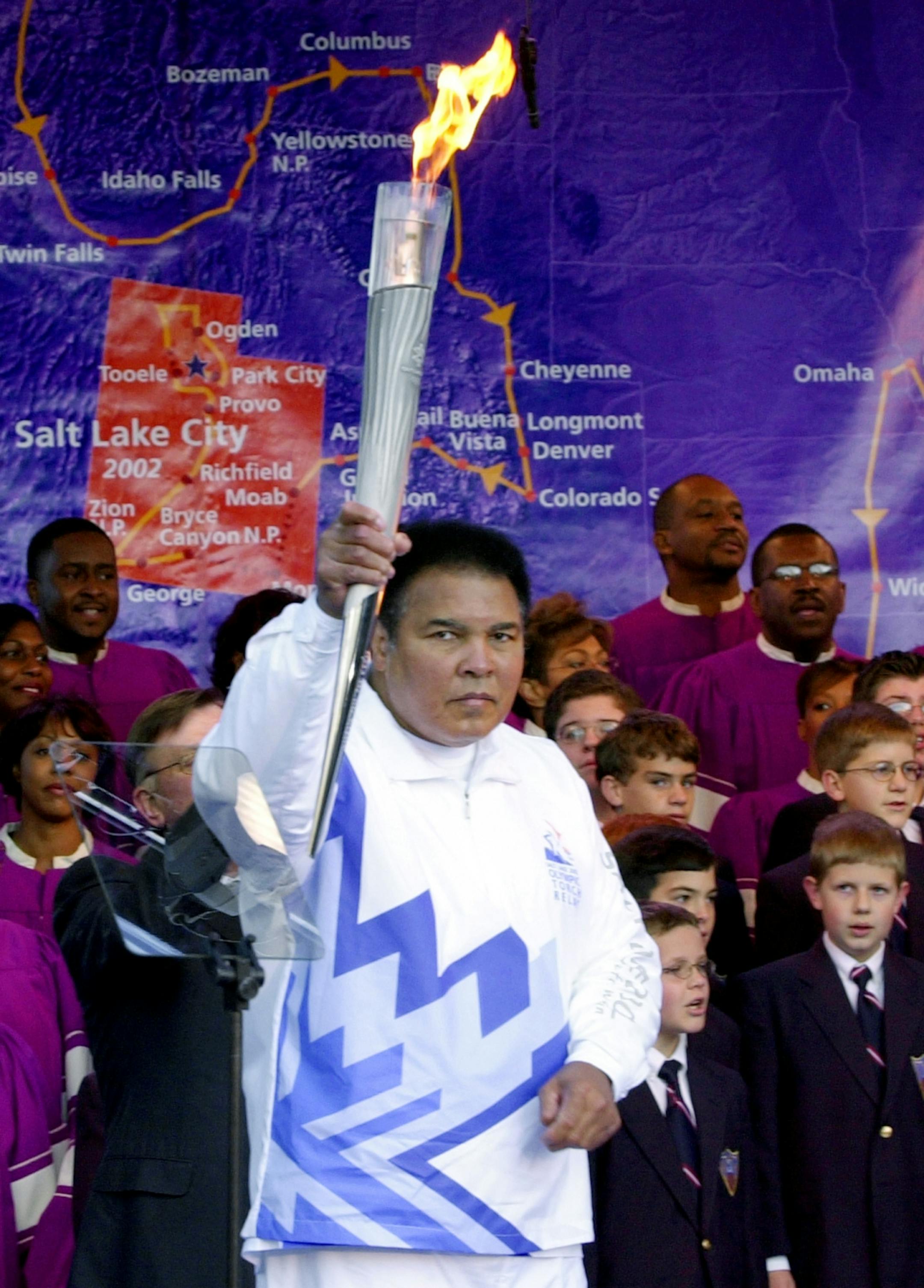 Boxing legend Muhammad Ali holds up the first Olympic torch lit from the cauldron in front of a map showing the torch's route during a ceremony at Centennial Olympic Park in Atlanta Tuesday, Dec. 4, 2001. The torch to light the cauldron was brought by jet from Athens, Greece., to Hartsfield Atlanta International Airport and then by motorcade to the park, beginning a 46-state tour to the 2002 Winter Olympics in Salt Lake City.