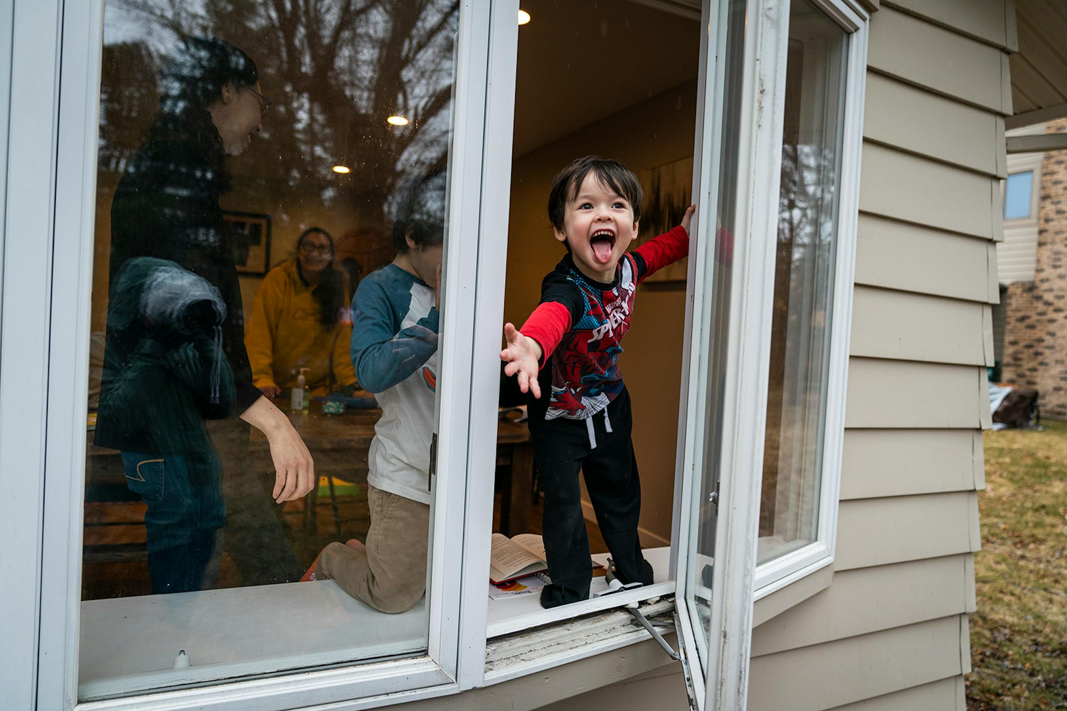 Parker Royce, 4, exclaimed as he felt the rain drops while reaching out the ground floor window of his Roseville home. Andrea Royce spent time homeschooling her three children with help from her friend that helps with childcare Carlota Bernal at Royce's home in Roseville on Wednesday, March 25, 2020. Parents are taking on the role of educators now that the schools are closed due to the COVID-19 pandemic.