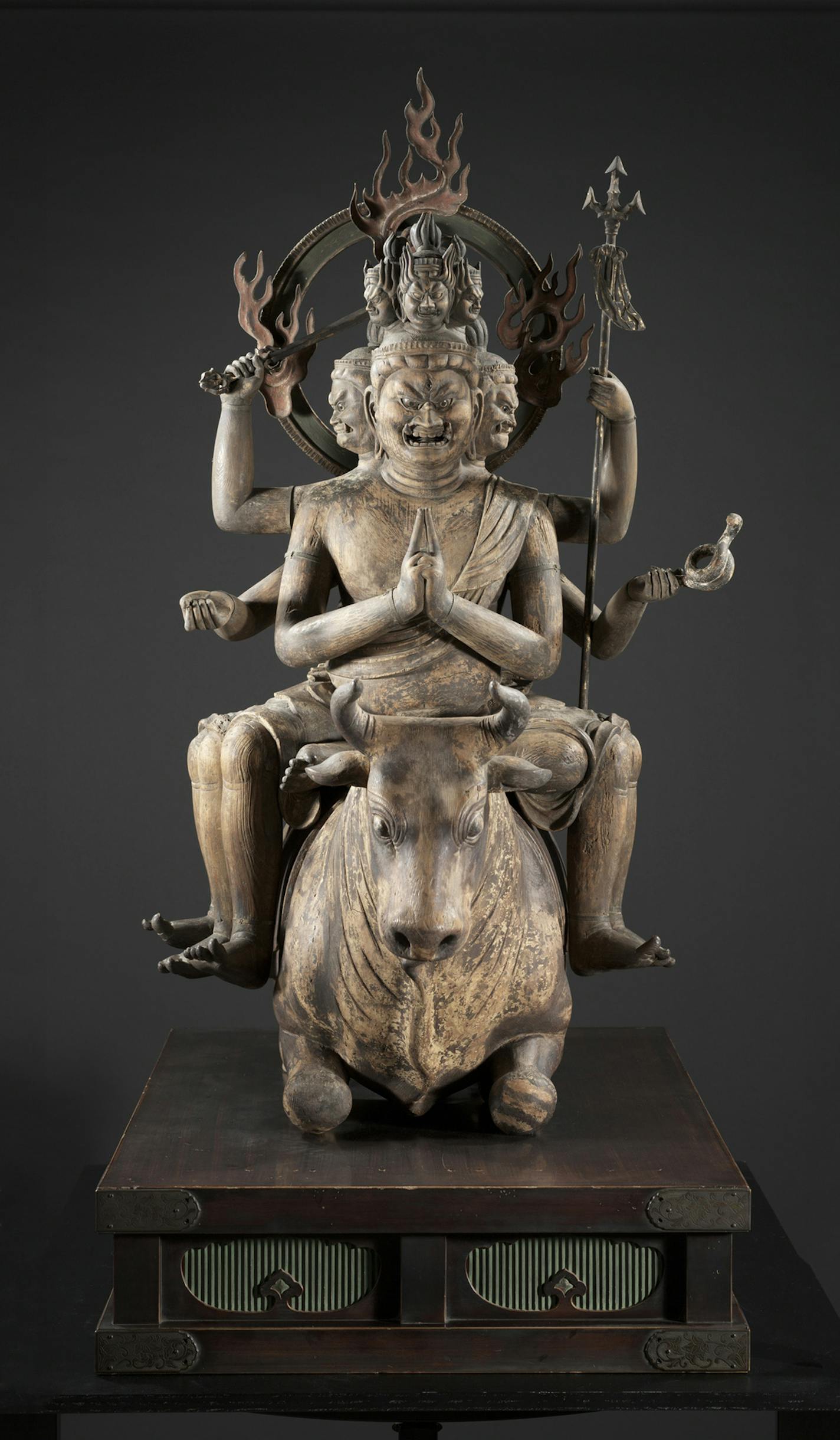 This unusually well-preserved life-size 13th-century wooden sculpture features a grimacing, multi-limbed Buddhist deity astride a kneeling bull.