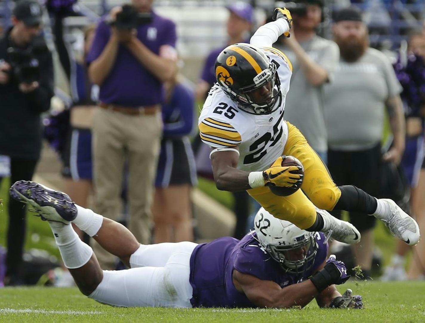 Iowa's Akrum Wadley (25) is tripped up by Northwestern's Nate Hall (32) during the first half of an NCAA college football game Saturday, Oct. 21, 2017, in Evanston, Ill.