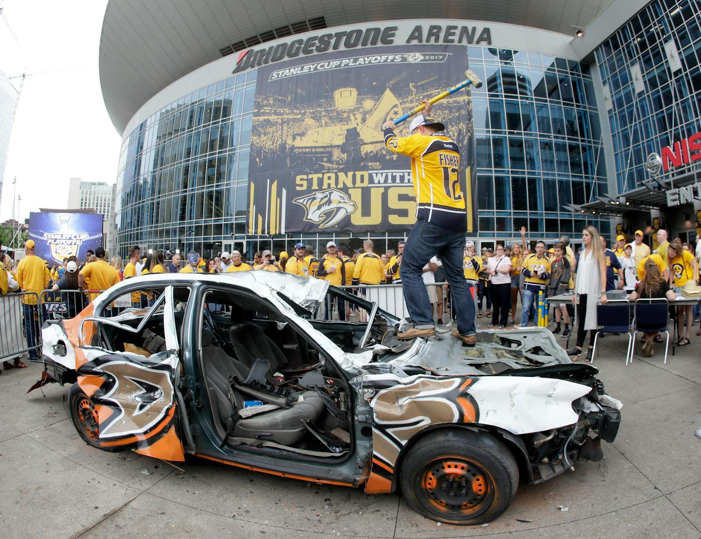 Nashville Predators fan Nick Olp swings a sledge hammer as he takes a turn beating up a car painted with Anaheim Ducks logos before Game 6 of the Western Conference final.