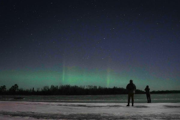 Mason and Allie Flack of White Bear Lake look out at the Northern Lights over Fall Lake in the Boundary Waters Canoe Area Wilderness on Nov. 30, 2023,