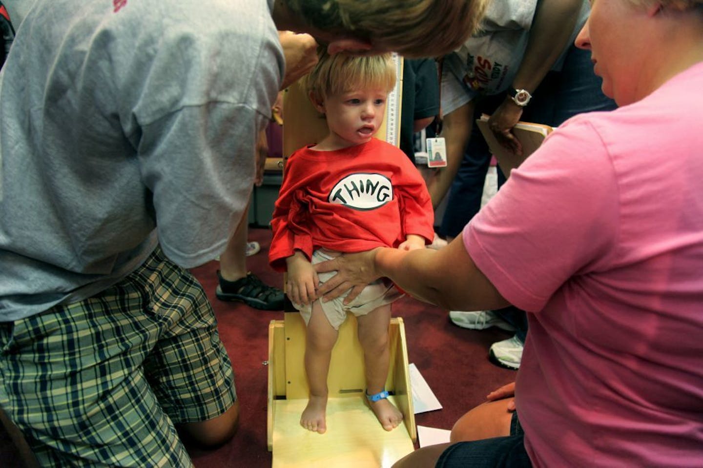 Beckett Poikonen, cq, 21 months, of Mound, MN, is guided by his mother Missy Poikonen as U of M students measure his height as part of the research process.