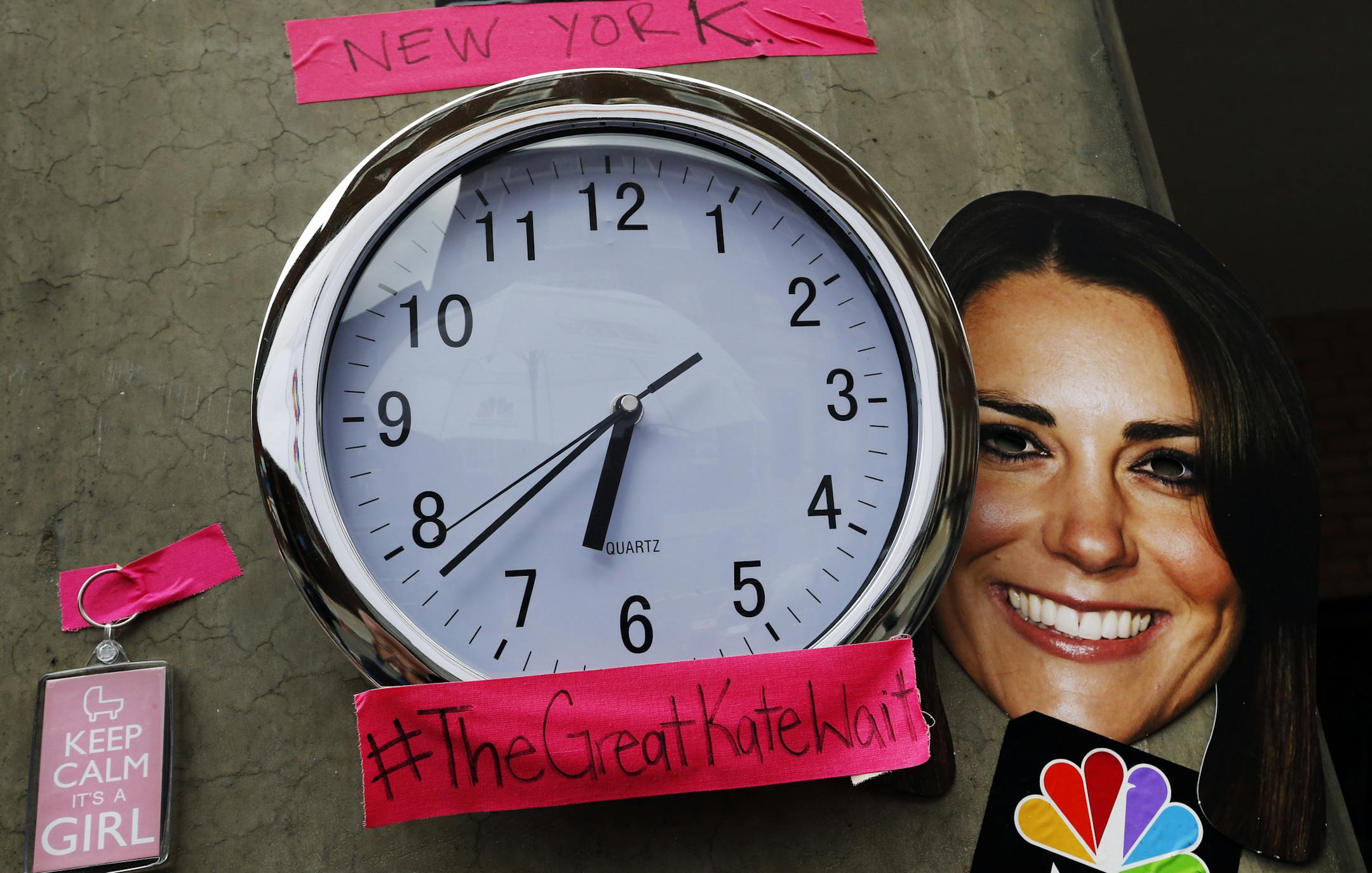 A mask depicting Britain's Duchess of Cambridge and a clock showing New York time, which were placed by members of the media, is seen across St. Mary's Hospital exclusive Lindo Wing in London, Sunday, July 21, 2013. Media are preparing for royal-mania as the Duchess is expected to give birth to the new third-in-line to the throne in mid-July, at the Lindo Wing. Cameras from all over the world are set to be jostling outside for an exclusive first glimpse of Britain's Prince William and the Duches