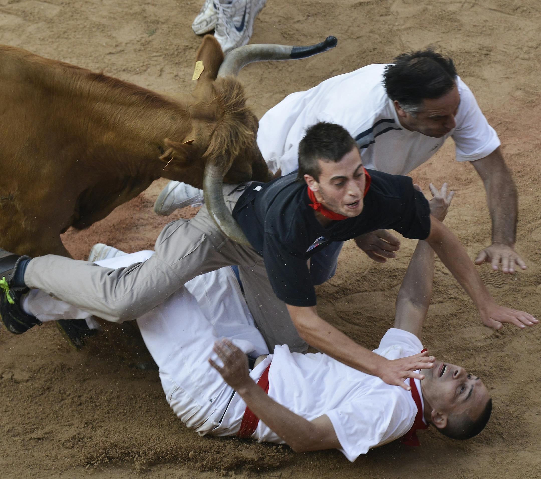 Revelers are pushed over by a bull at the end of the last running of the bulls at the San Fermin festival, in Pamplona Spain on Sunday, July 14, 2013. Revelers from around the world arrive to Pamplona every year to take part in some of the eight days of the running of the bulls glorified by Ernest Hemingway's 1926 novel "The Sun Also Rises." (AP Photo/Alvaro Barrientos)