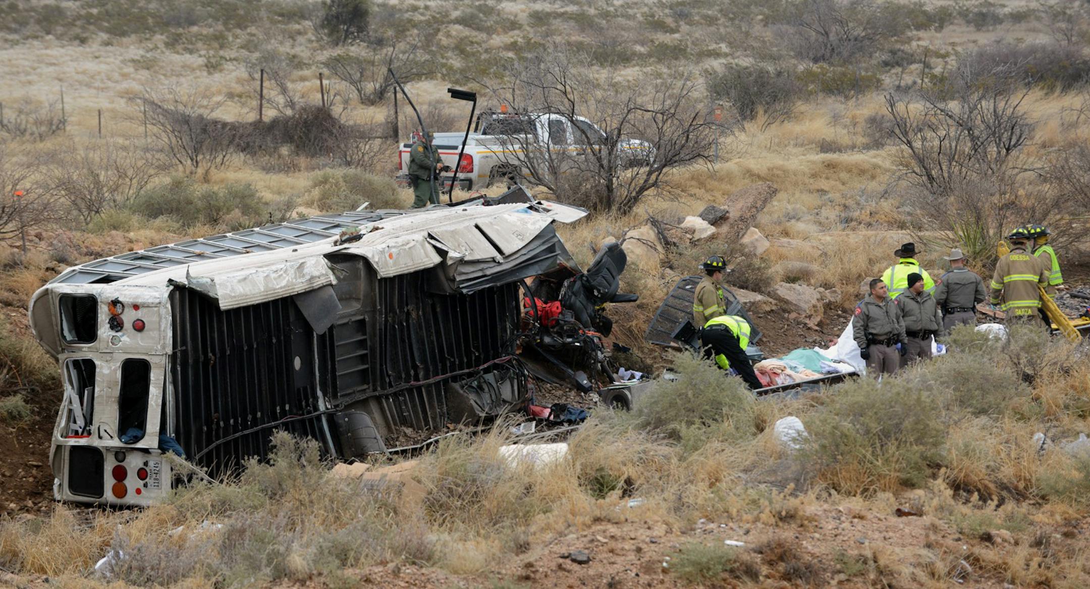 Officials investigate the scene of a prison transport bus crash in Penwell, Texas, Wednesday, Jan. 14, 2015. Law enforcement officials said the bus carrying prisoners and corrections officers fell from an overpass in West Texas and crashed onto train tracks below, killing an unspecified number of people. (AP Photo/The Odessa American, Mark Sterkel)