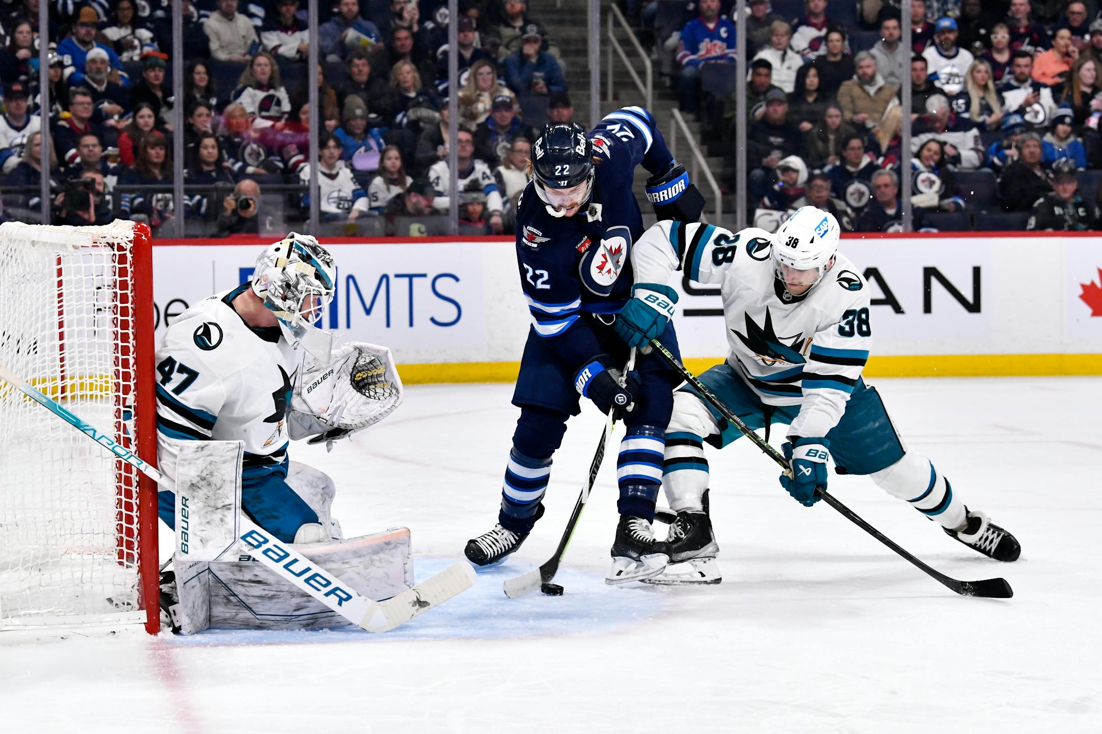 San Jose Sharks' Mario Ferraro (38) and Winnipeg Jets' Mason Appleton (22) battle for the puck in front of Sharks goaltender James Reimer (47) during second-period NHL hockey game action in Winnipeg, Manitoba, Monday April 10, 2023. (Fred Greenslade/The Canadian Press via AP)