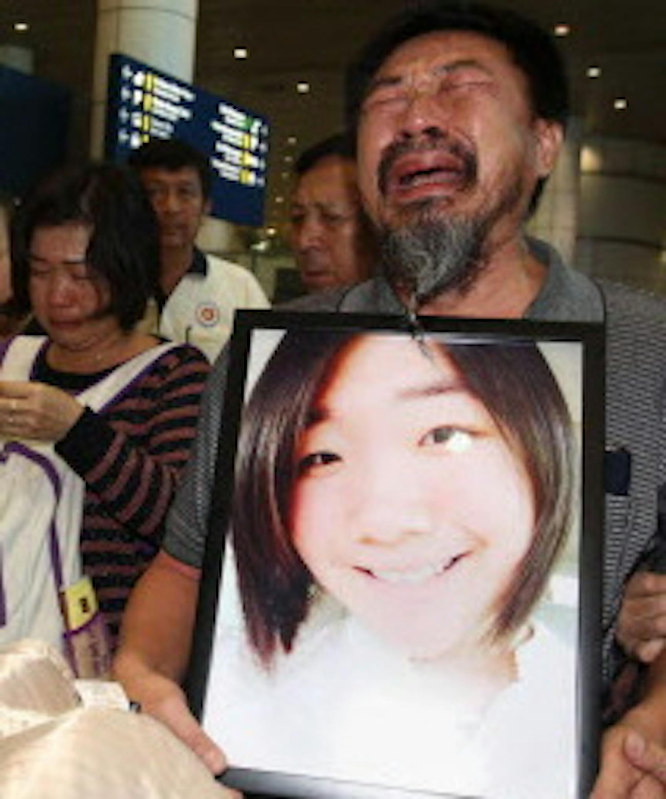 In this Jan. 5, 2015 photo, Tan Chin Hin, center, father of a stampede victim, Tan Wei, cries, holding her portrait, as he arrives back from Shanghai, with the body of his late daughter, at Kuala Lumpur International Airport in Kuala Lumpur. Thirty six died in the stampede during New Year's celebrations in downtown Shanghai, city officials said - the worst disaster to hit one of China's showcase cities in recent years. (AP Photo) MALAYSIA OUT, NO ARCHIVE, NO SALE