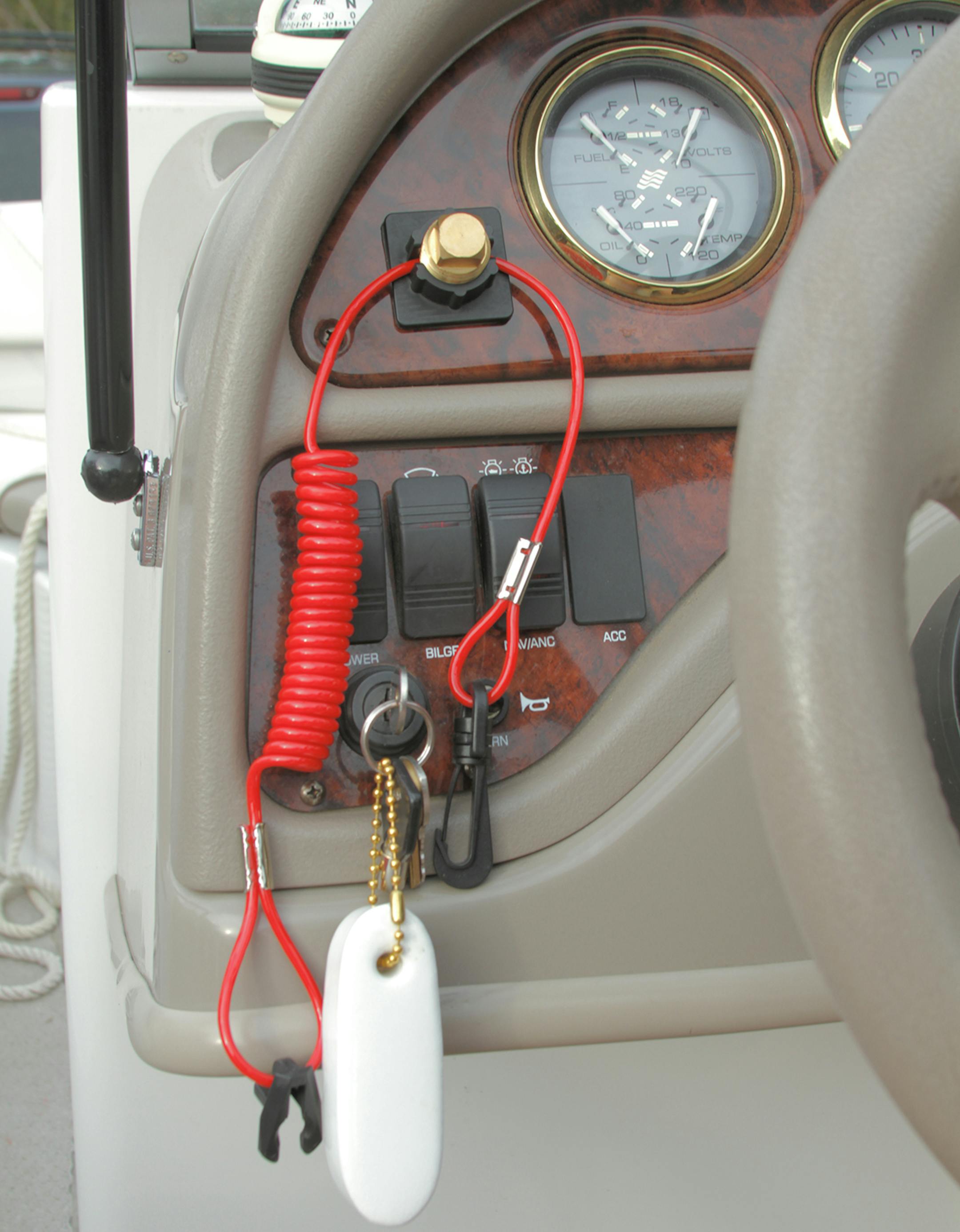 The black plastic Plug Dock device is shown holding a brass boat plug and orange kill-switch tether. The boater can't start the engine until the kill-switch tether is connected near the engine. Photo courtsey Jon Harkness