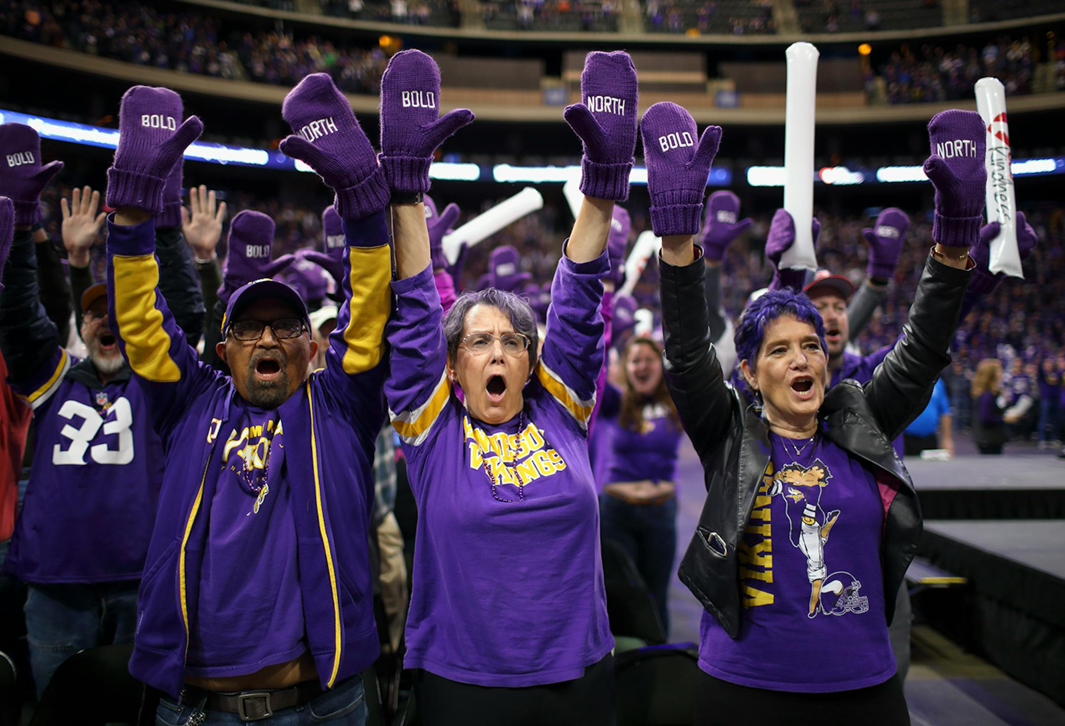 Wearing mittens that everyone attending the orientation received, Super Bowl LII volunteers Domingo Martinez, Gail Martinez, and Carol Prettyman, from left, chanted "Bold" and "North" during the program.