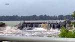 This image taken from video provided by WGBA-TV, shows water breaching a section of a dam, left, along the Little Wolf River, Friday, July 5, 2024, in