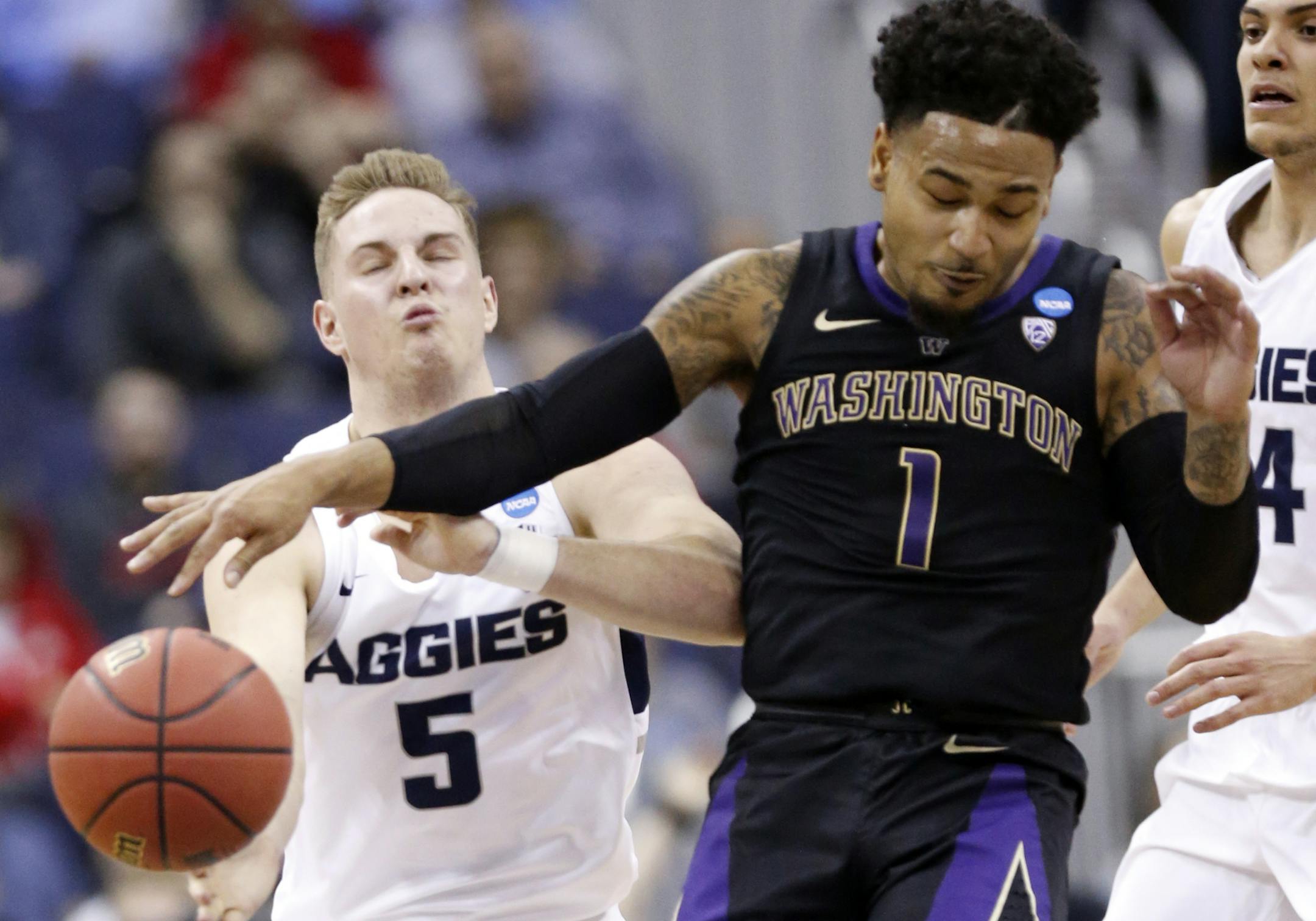 Washington's David Crisp (1) and Utah State's Sam Merrill (5) battle for the ball in the first half during a first round men's college basketball game in the NCAA Tournament in Columbus, Ohio, Friday, March 22, 2019. (AP Photo/Paul Vernon)