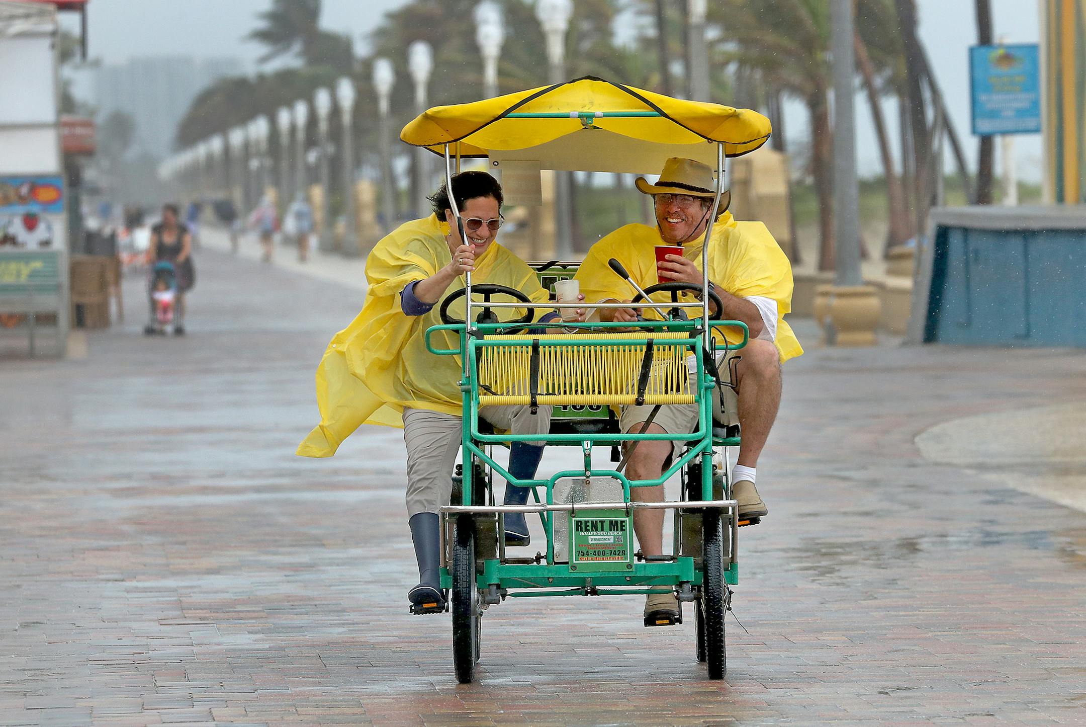 Despite the rain, Evelyn Padilla and Luis Calzada ride back from Nick's Bar and Grill to their hotel on Hollywood Beach. Heavy rain, wind gusts, strong rip currents, possible flash flooding and perhaps even tornadoes are forecast across South Florida during the Memorial Day weekend. (Mike Stocker/Sun Sentinel/TNS)