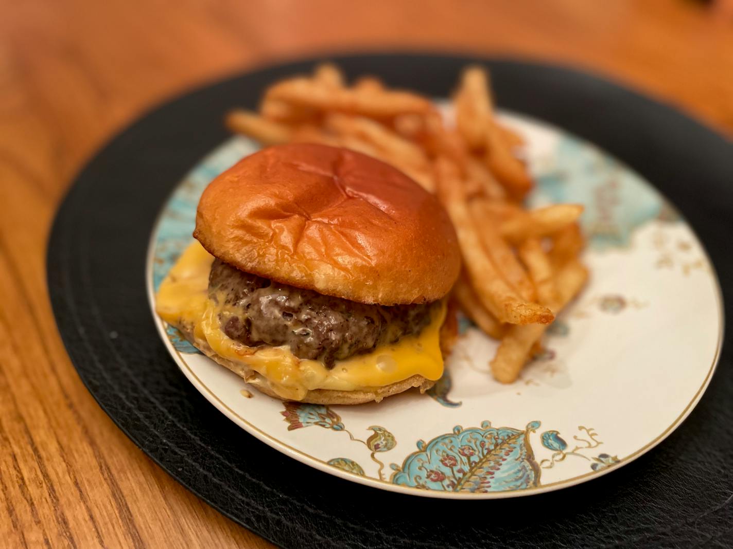 The Chapli burger with a slice of American cheese on a plate next to a pile of fries.