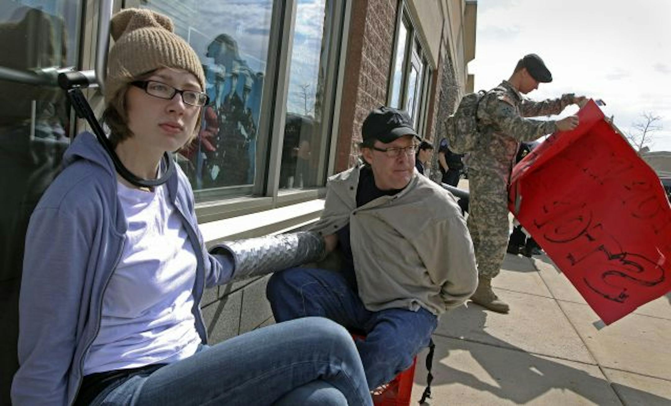 In Brooklyn Center, police arrested four demonstrators, including Leigh York, at left, and Robert Kolstad, who had locked themselves to the front doors of a recruitment center Thursday.
