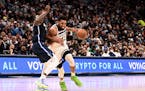 Dallas Mavericks' Dorian Finney-Smith, left, defends as the Timberwolves' Karl-Anthony Towns, right, drives to the basket in the second half