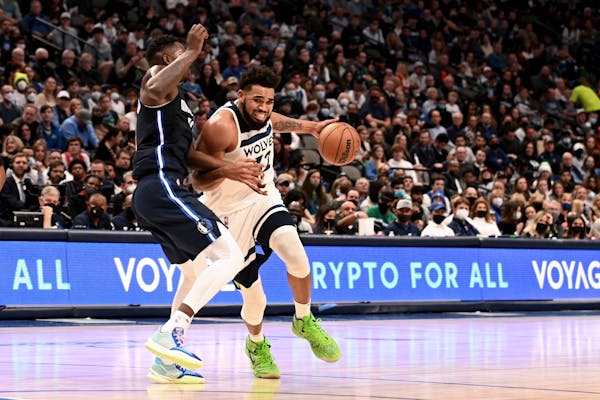 Dallas Mavericks' Dorian Finney-Smith, left, defends as the Timberwolves' Karl-Anthony Towns, right, drives to the basket in the second half