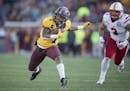 Minnesota's running back Rodney Smith rushed with the ball chased by Nebraska's linebacker Marcus Newby during the third quarter as the Gophers took o