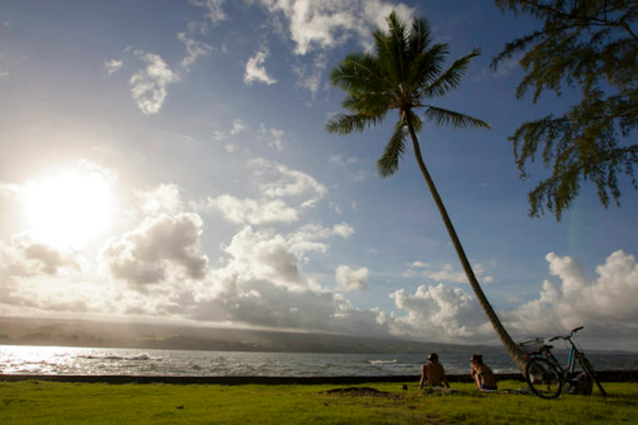 FILE - In this Aug. 30, 2015, file photo, Keenin Ide, left, of Hilo, Hawaii, and Medea Yankova, of Sofia, Bulgaria, sit near Hilo Bay in Hilo, Hawaii. The Big Island visitors bureau and Hawaii County have launched a campaign that aims to create a more conscientious tourism industry on the Big Island. The Island of Hawaii Visitors Bureau Executive Director Ross Birch and county Managing Director Will Okabe presented the new "Pono Pledge" at a Thursday, Sept. 20, 2018, event, the Hawaii Tribune-He