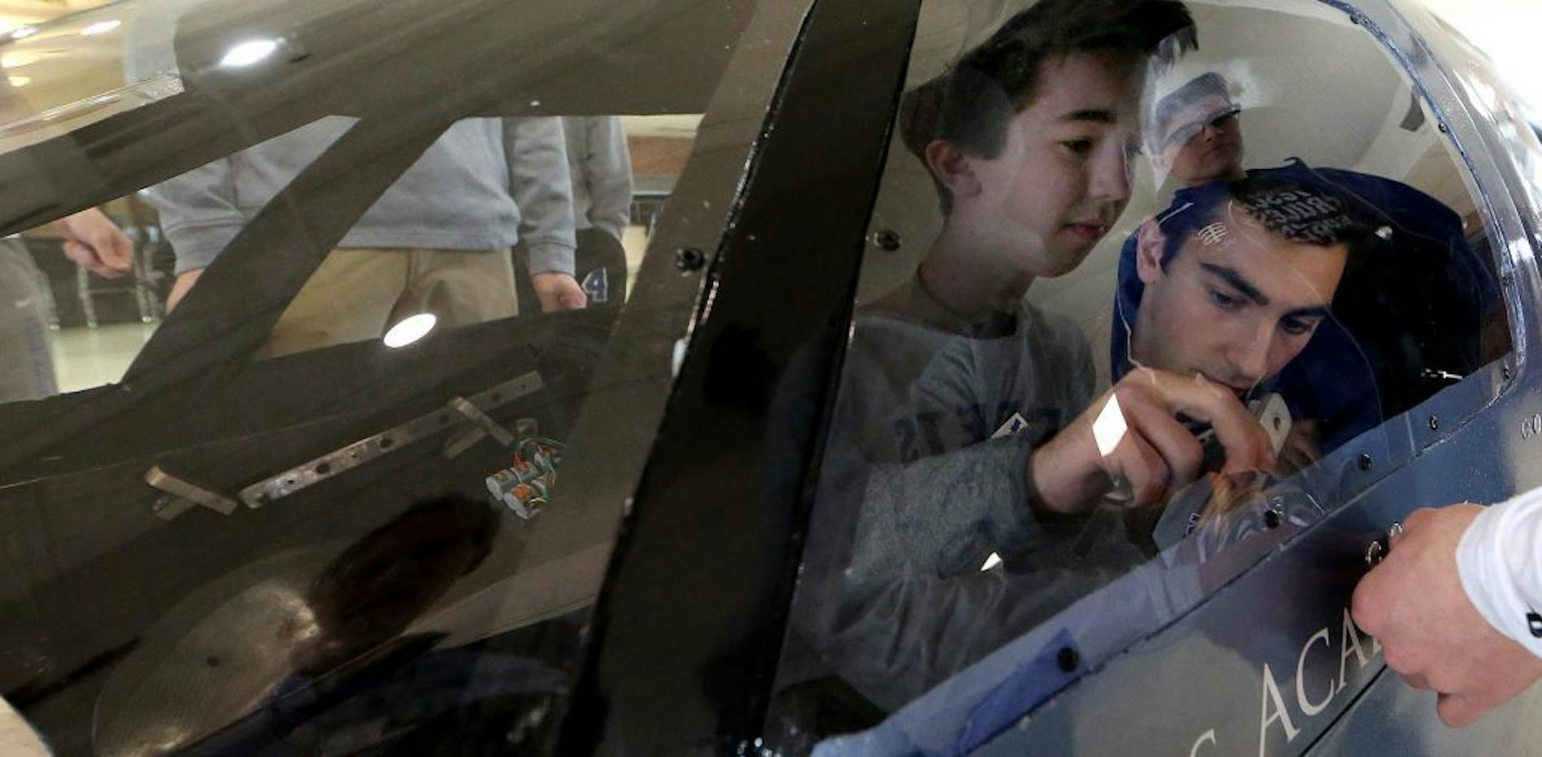 Tim D'Agostino, lower right, and Patrick Gaylord secured the top portion and windshield to the main body of the vehicle they were building for the Shell Eco-Marathon.