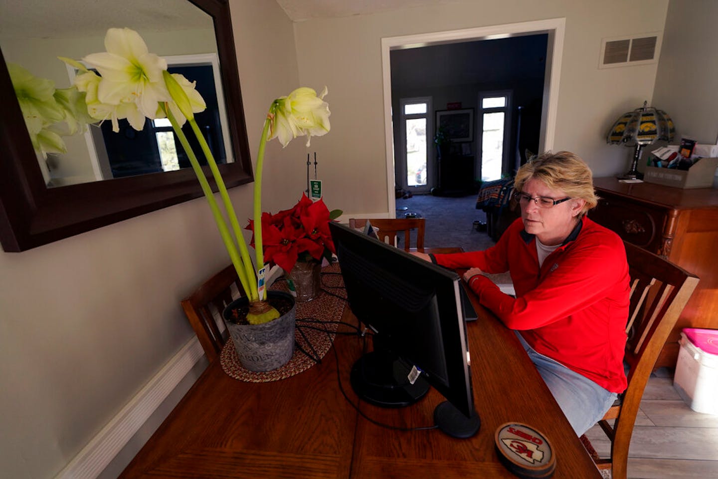 Keli Paaske searches for jobs online from the dining room of her home in Olathe, Kan. Friday, Dec. 4, 2020. Paaske was laid off in August from a company supplying fire doors to hospitals after being furloughed for five months and has struggled to find a new job. (AP Photo/Charlie Riedel)