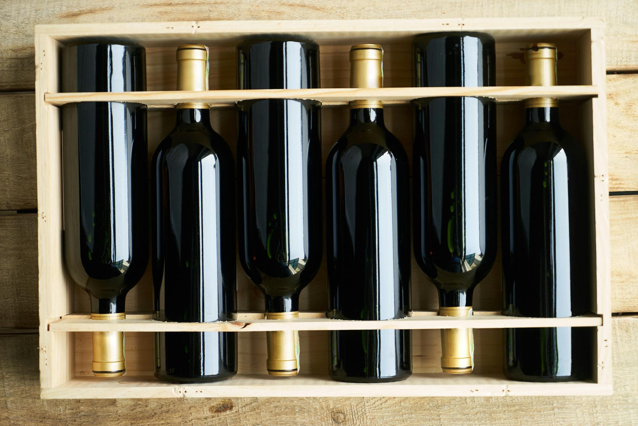 Top view of a case of cabernet sauvignon wine bottles. Wooden box with collection of six wine bottle