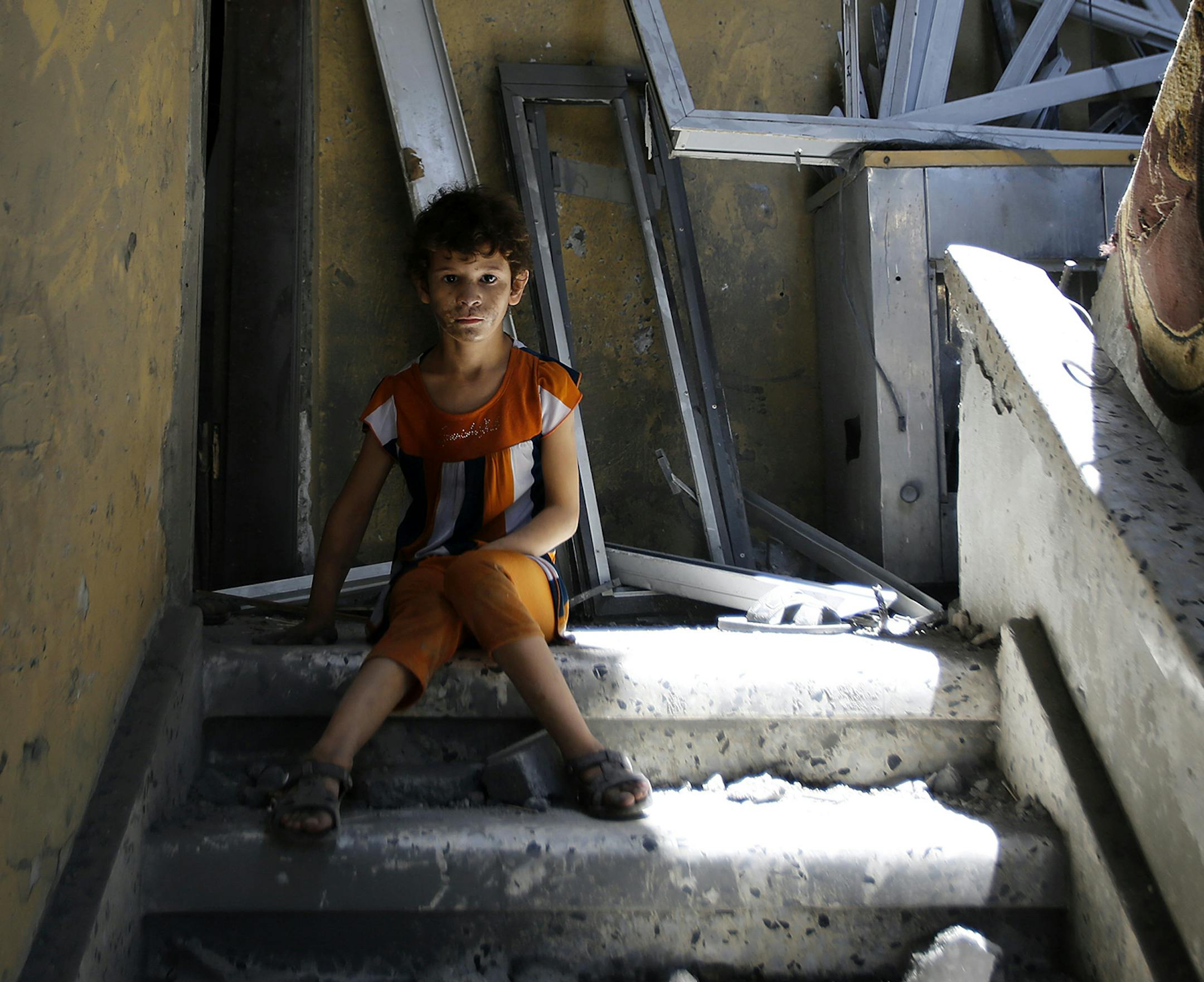 A Palestinian boy sits in the stairwell of his home in the heavily bombed Gaza City neighborhood of Shijaiyah, close to the Israeli border, Friday, Aug. 1, 2014. A three-day Gaza cease-fire that began Friday quickly unraveled, with Israel and Hamas accusing each other of violating the truce. (AP Photo/Hatem Moussa) ORG XMIT: MIN2014080115405132