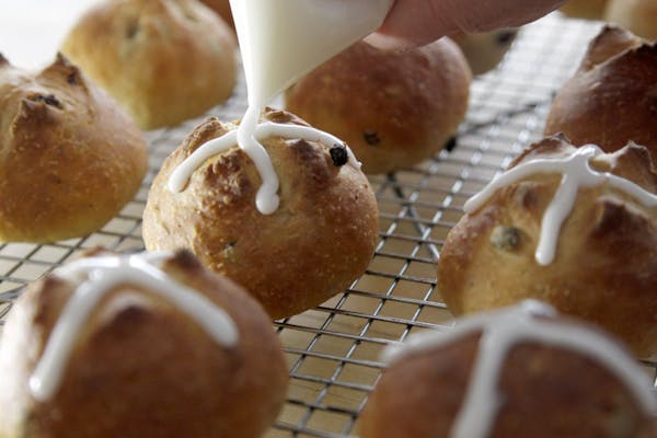 When the buns are done baking, drizzling icing into crosses.