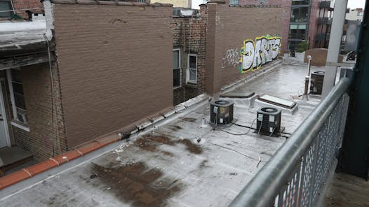 Brown paint and new graffiti covers a building's side wall that formerly displayed the mural, as seen from the Paulina Brown Line 