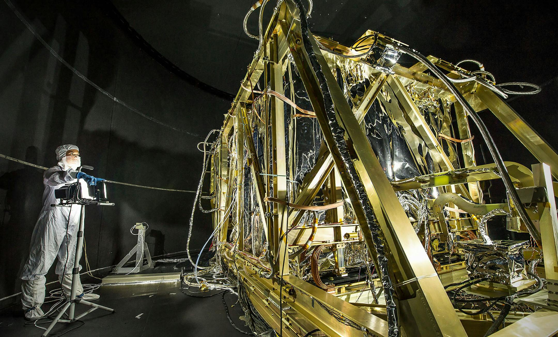 Dressed in a protective suit, NASA photographer Desiree Stover shines a light on a portion of the James Webb Space Telescope. Its infrared cameras will be able to see faraway things that are moving away from us. Illustrates TELESCOPE (category a), by Eric Niiler, special to The Washington Post. Moved Tuesday, November 18, 2014. (MUST CREDIT: Chris Gunn/NASA.) ORG XMIT: MIN1411182051470723