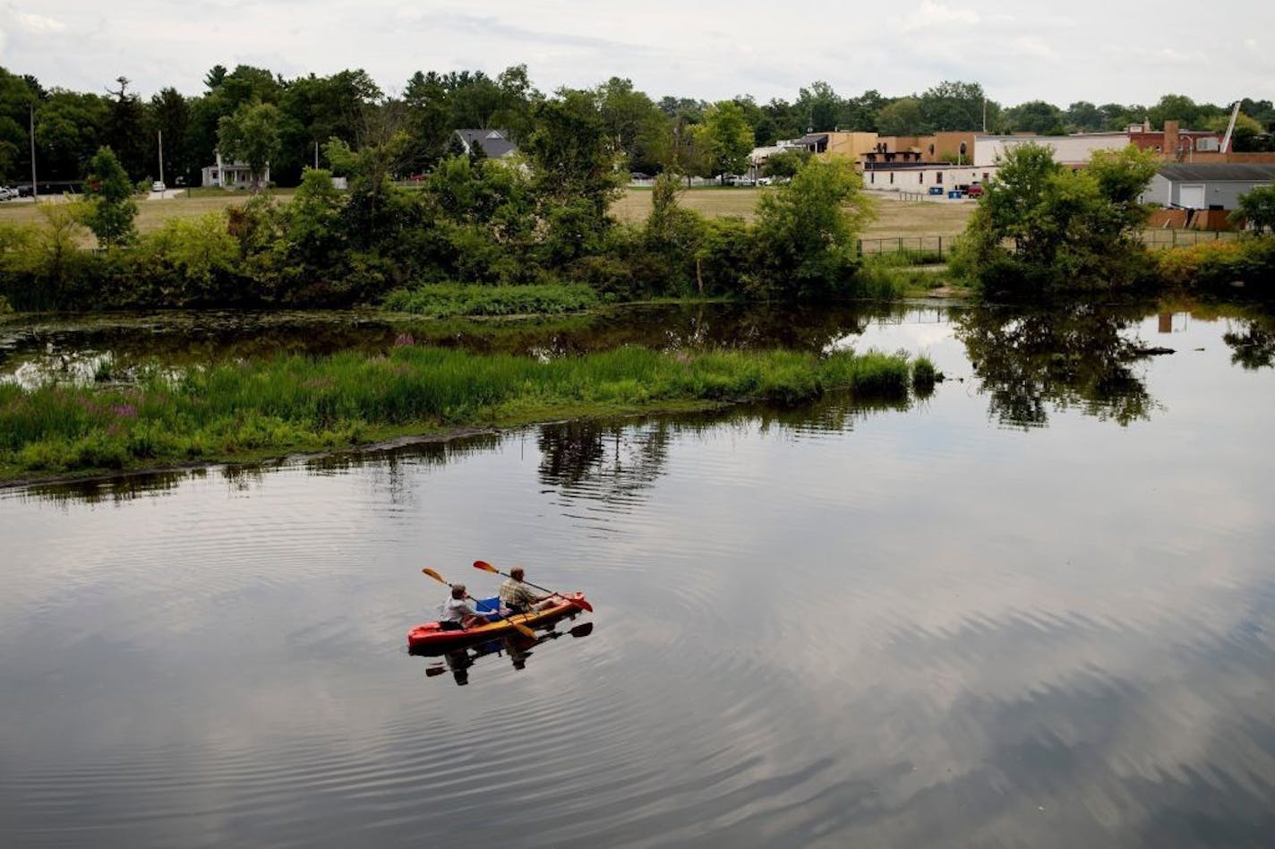 FILE- In this Monday, Aug. 14, 2017 file photo, a couple kayak on the Rogue River adjacent to where Wolverine World Wide's tannery once stood, in Rockford, Mich. The Michigan Department of Environmental Quality is investigating the connection between old waste drums in the area and an old Wolverine World Wide tannery waste dump nearby. Some private wells in the area have tested positive for elevated levels of per- and polyfluoroalkyl substances called PFAS, also called perfluorinated chemicals,