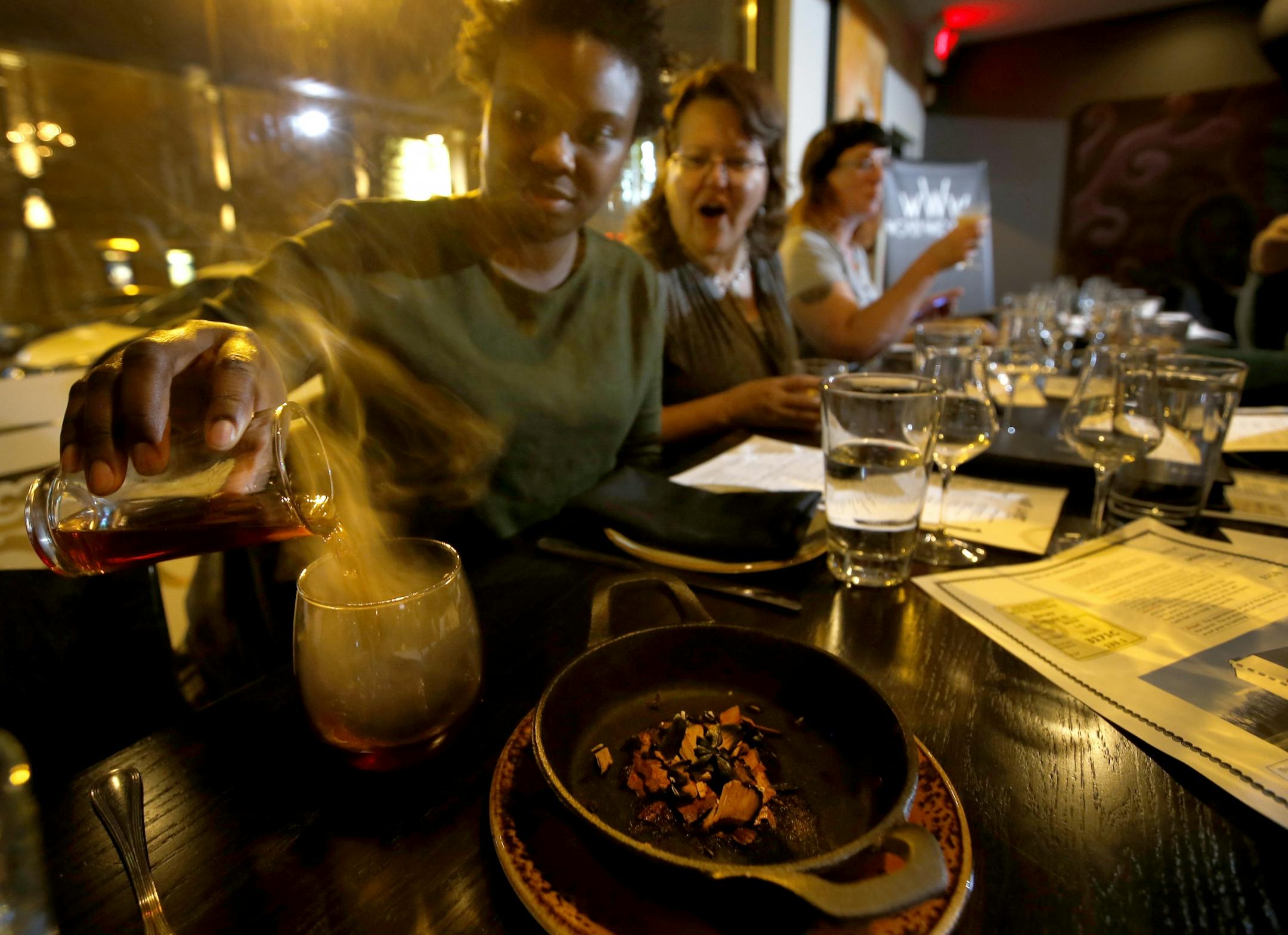 Nichole Macintosh poured her Smoked Manhattan into a glass that was smoked in apple wood to enhance the flavor of her signature cocktail at coup d'etat in Minneapolis.