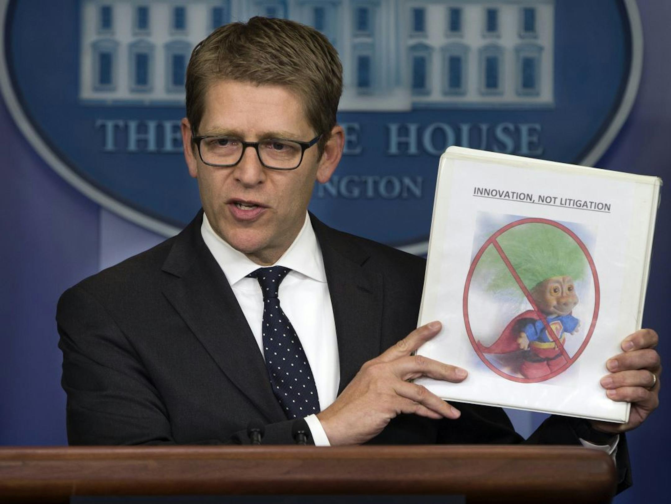 White House press secretary Jay Carney holds up a folder with an image of a troll and the words "innovation, not litigation" during the daily press briefing at the White House in Washington, Tuesday, June 4, 2013. Carney pointed out that the Obama administration is taking action to limit frivolous patent lawsuits, or "patent trolling."