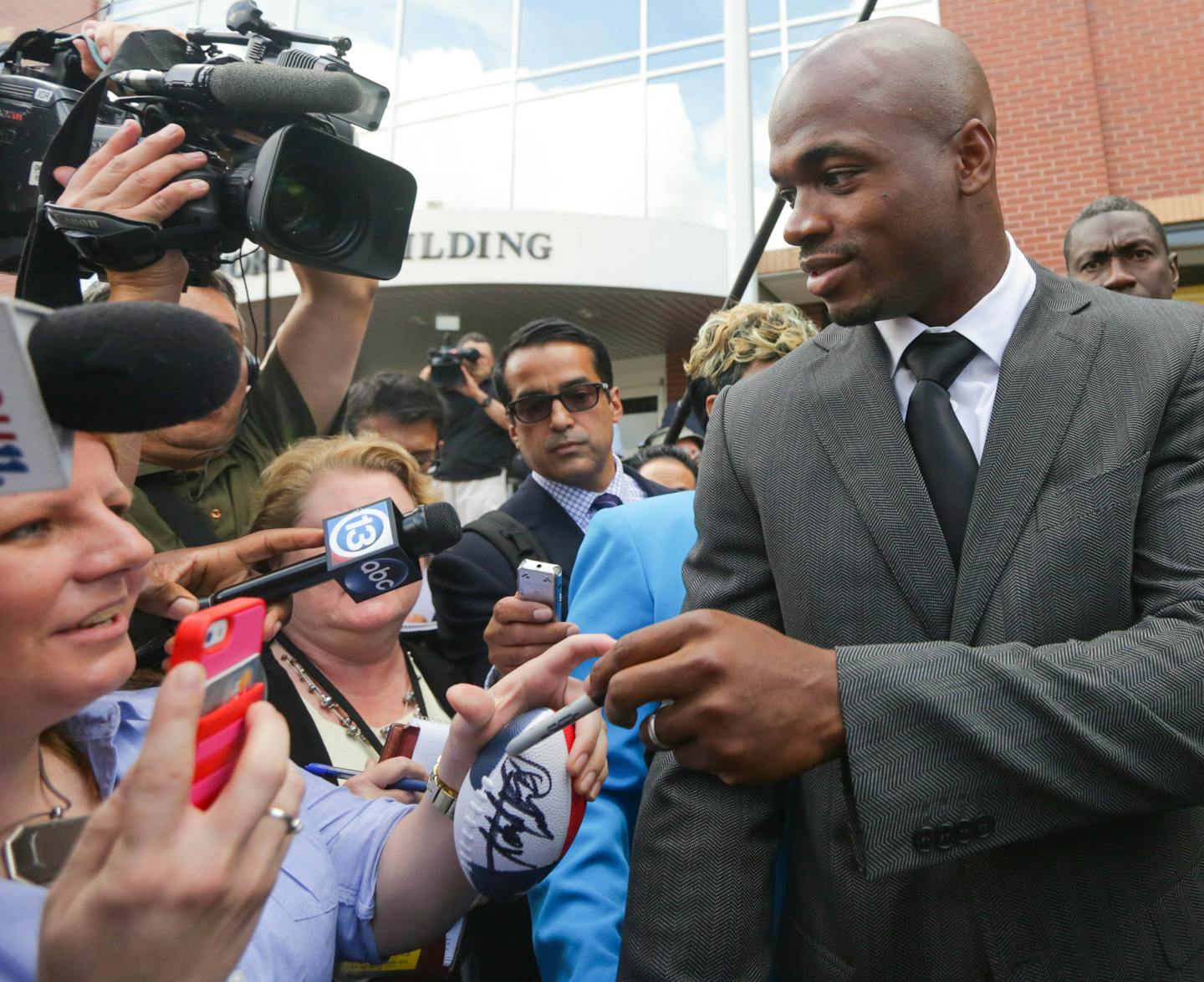 Minnesota Vikings running back Adrian Peterson signs an autograph as he leaves court in Conroe, Texas, Wednesday, Oct.. 8, 2014. A judge tentatively set a Dec. 1 trial date for Peterson on a charge of felony child abuse for using a wooden switch to discipline his 4-year-old son earlier this year. (AP Photo/Houston Chronicle, Billy Smith II)