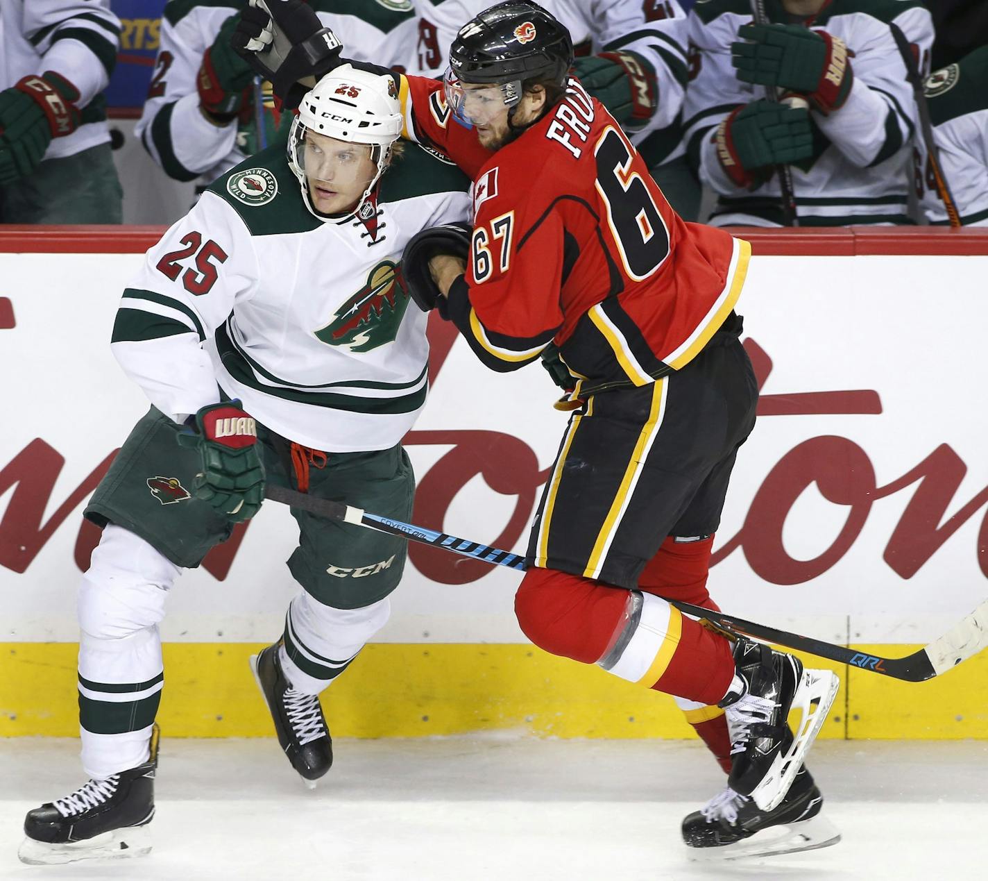 Minnesota Wild's Jonas Brodin, left, from Sweden, battles with Calgary Flames' Michael Frolik, from the Czech Republic, during first-period NHL hockey game action in Calgary, Alberta, Friday, Dec. 2, 2016. (Larry MacDougal/The Canadian Press via AP)