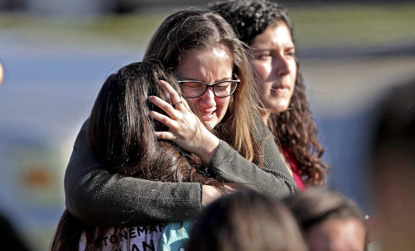 FILE - In this Wednesday, Feb. 14, 2018 file photo, students released from a lockdown embrace following following a shooting at Marjory Stoneman Douglas High School in Parkland, Fla. A week after a shooter slaughtered more than a dozen people in the Florida high school, thousands of protesters, including many angry teenagers, swarmed into the state Capitol on Wednesday, Feb. 21, calling for changes to gun laws, a ban on assault-type weapons and improved care for the mentally ill. (John McCall/So