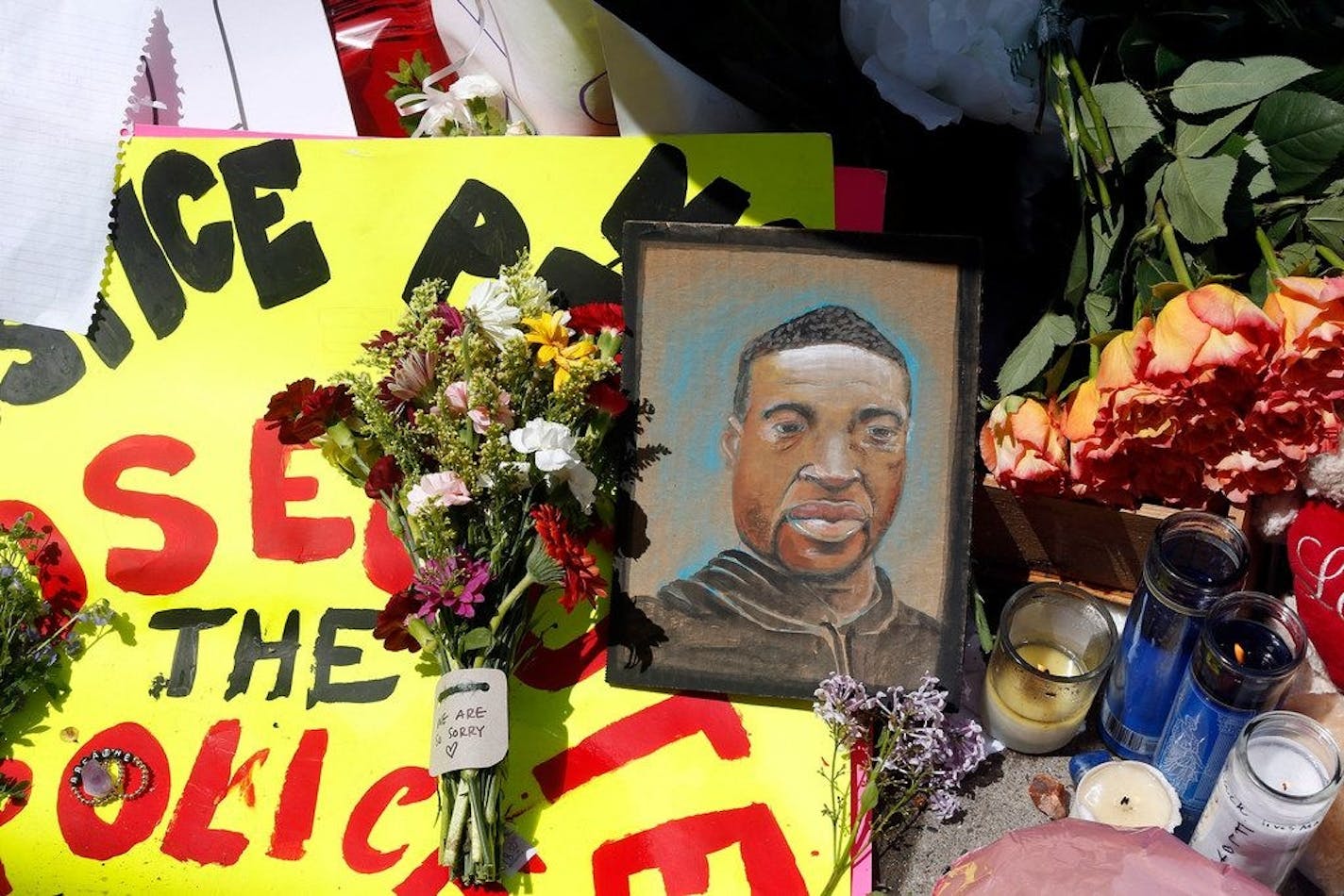 A chain portrait of George Floyd is part of the memorial for him, Wednesday, May 27, 2020, near the site of the arrest of Floyd who died in police custody Monday night in Minneapolis after video shared online by a bystander showed a white officer kneeling on his neck during his arrest as he pleaded that he couldn't breathe. (AP Photo/Jim Mone) Jim Mone